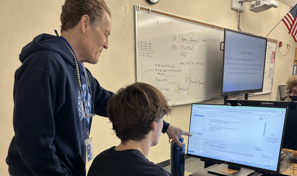 Teacher with student working on computer code
