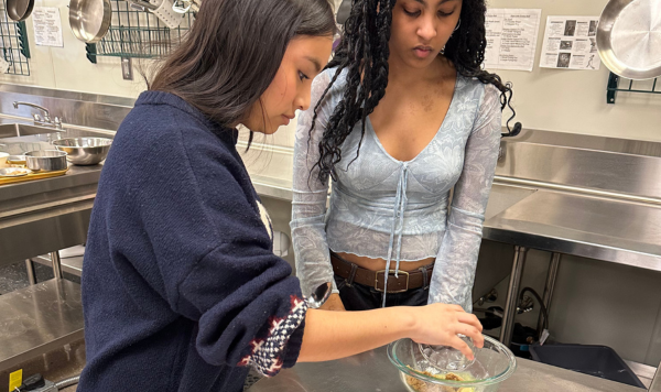 Two students mixing cooking ingredients